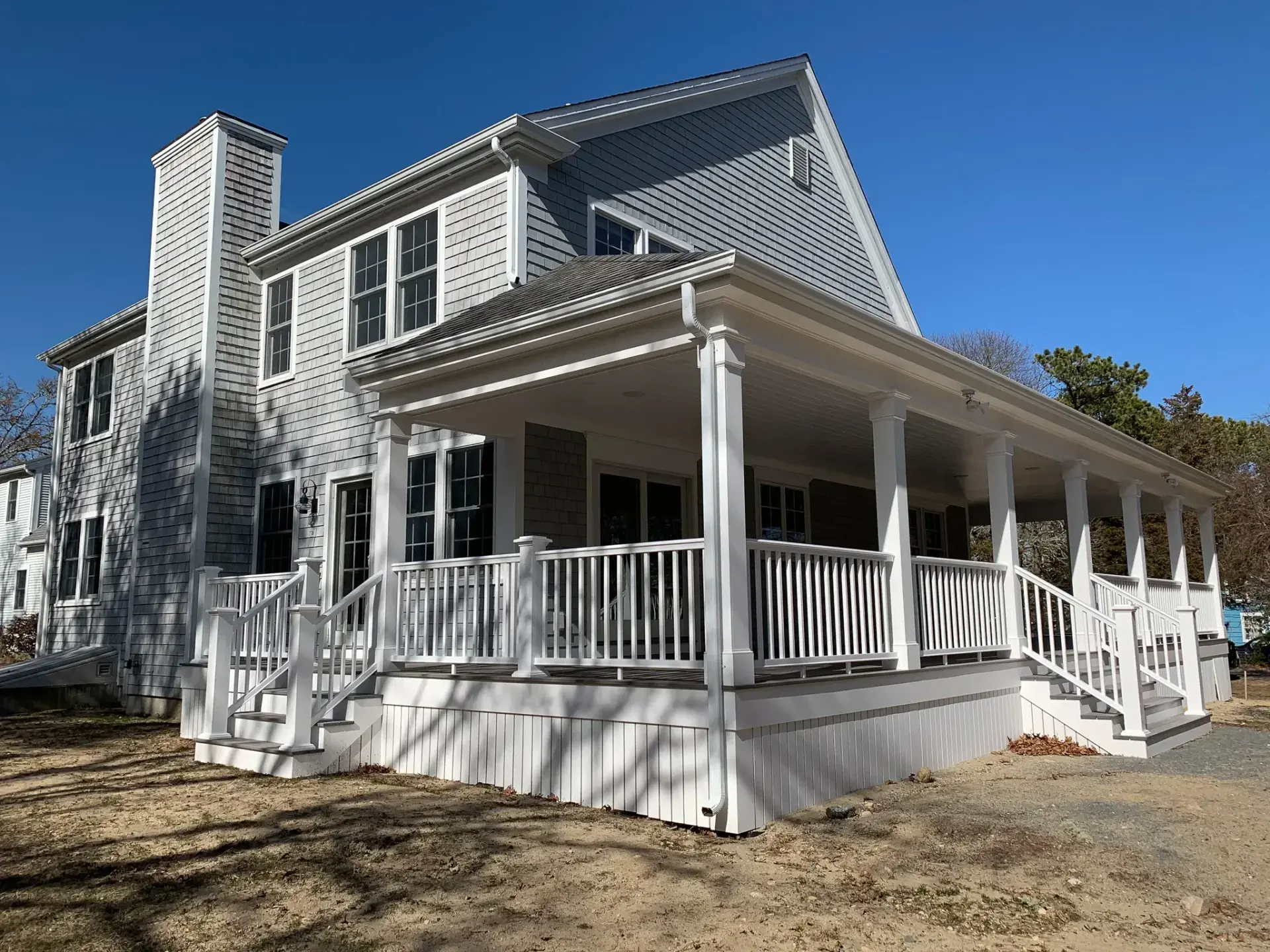 New custom home with wraparound farmer's porch and white railings by Tuleika Building Company